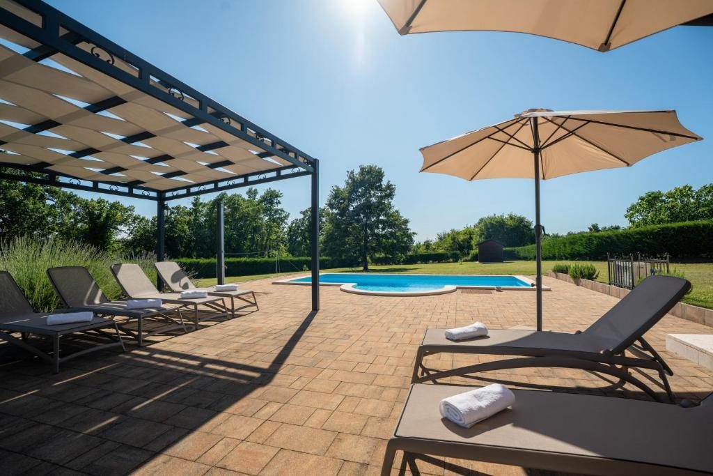 Ležaljke, suncobrani i pergola uz bazen Ville Elide