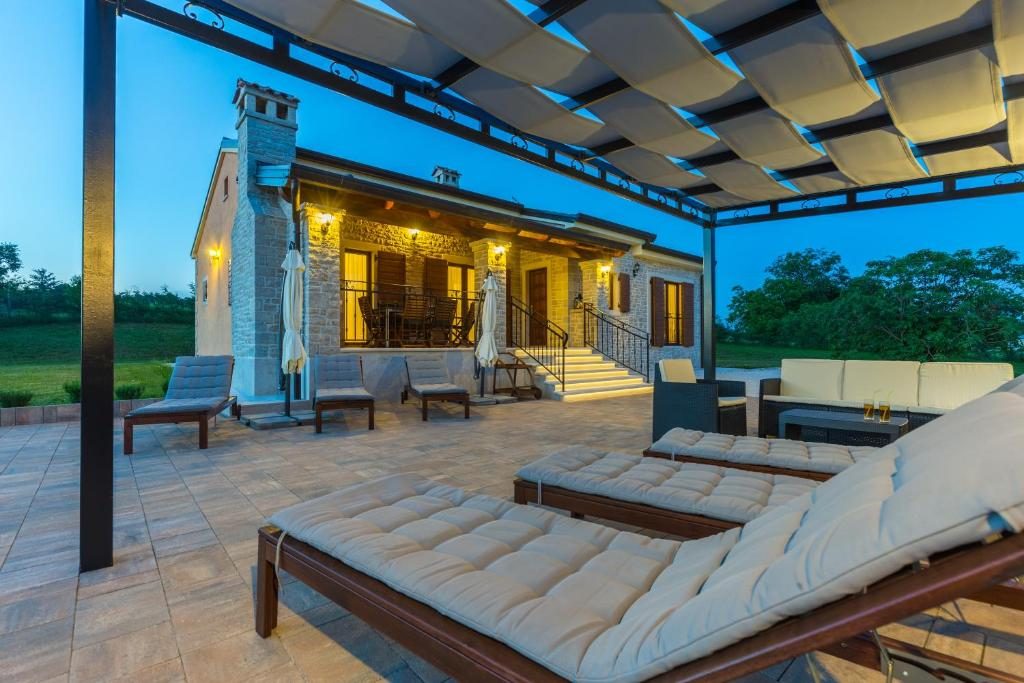 Ležaljke i lounge ispod pergole Ville Elide ljetne večeri